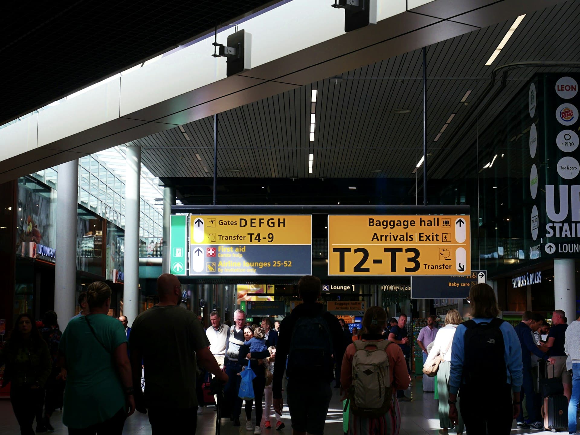 Travellers walking through a bright airport terminal concourse