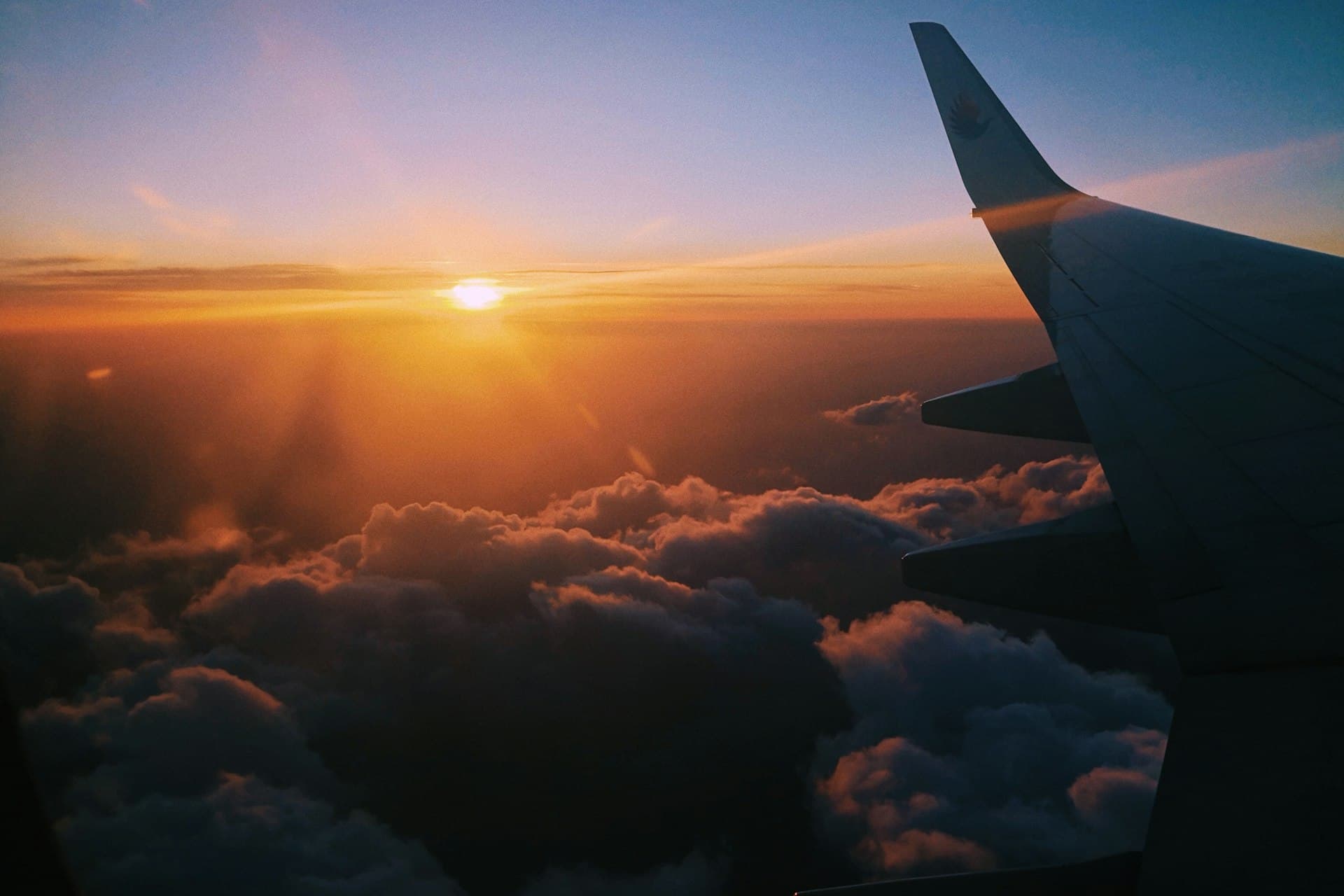 Airplane flying over a sea of clouds during golden hour