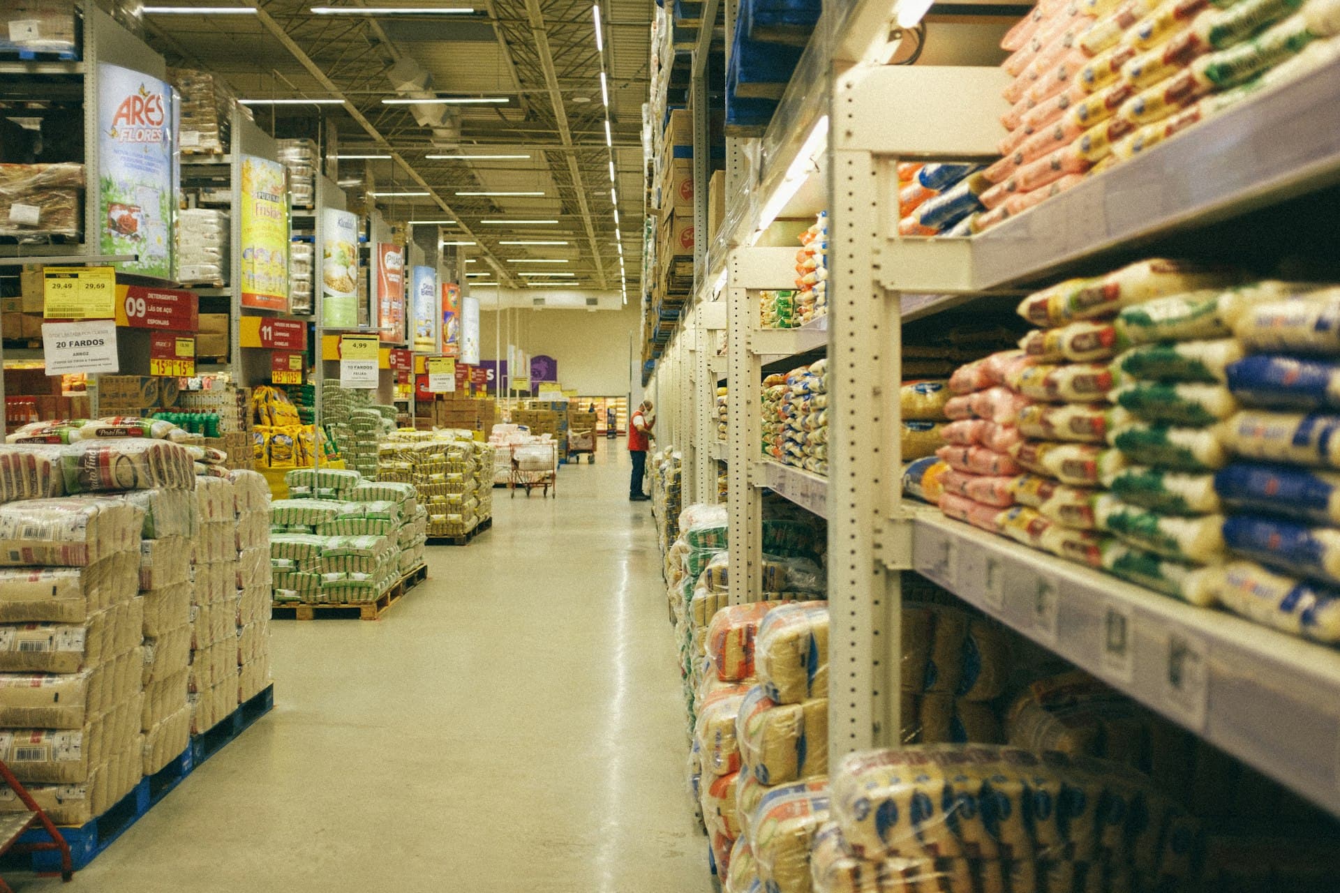 Warehouse club aisle with bulk goods stacked on tall industrial shelving