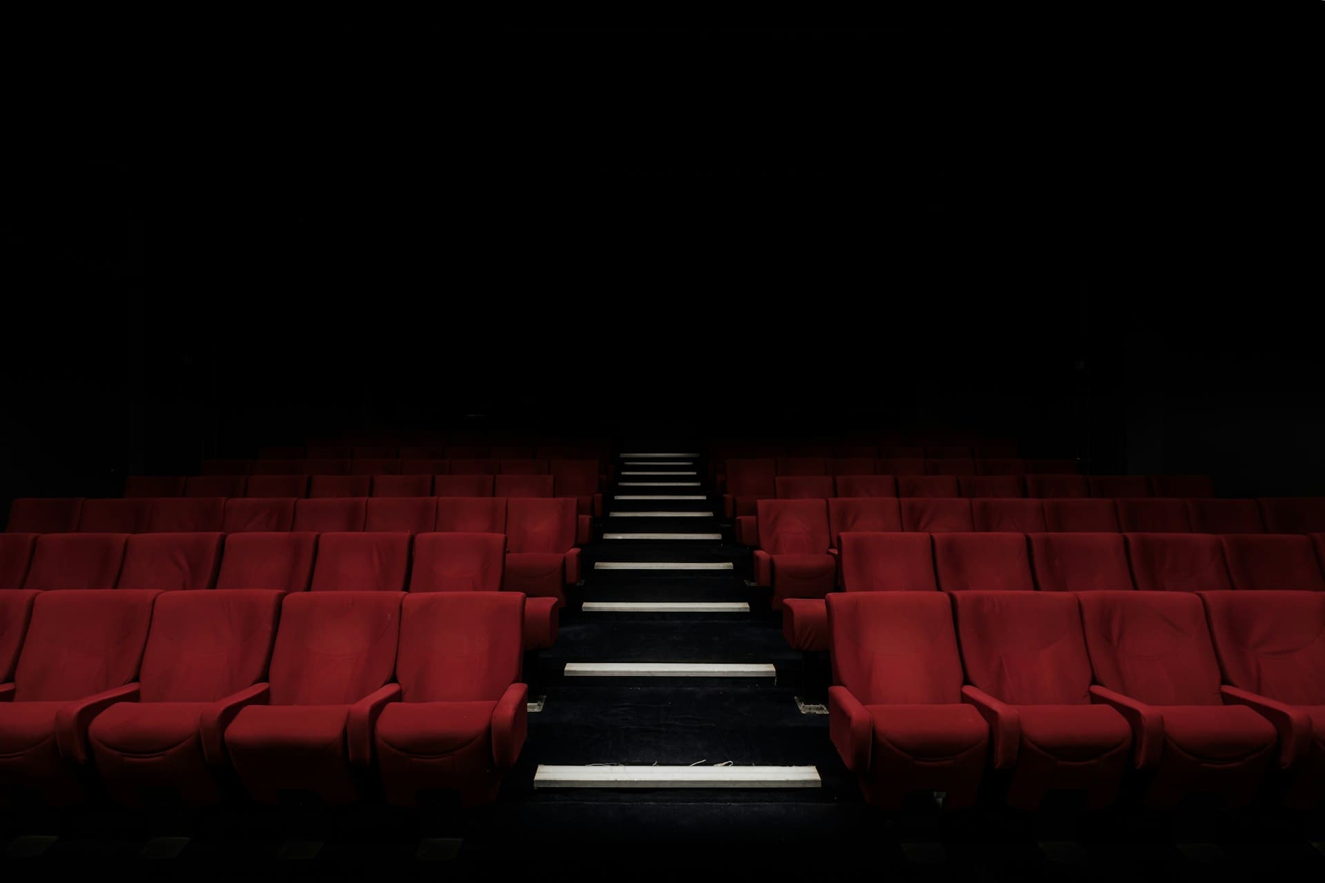 Rows of red cinema seats in an empty theatre
